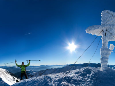 Skitourengeher am Gipfelkreuz bei Sonnenschein