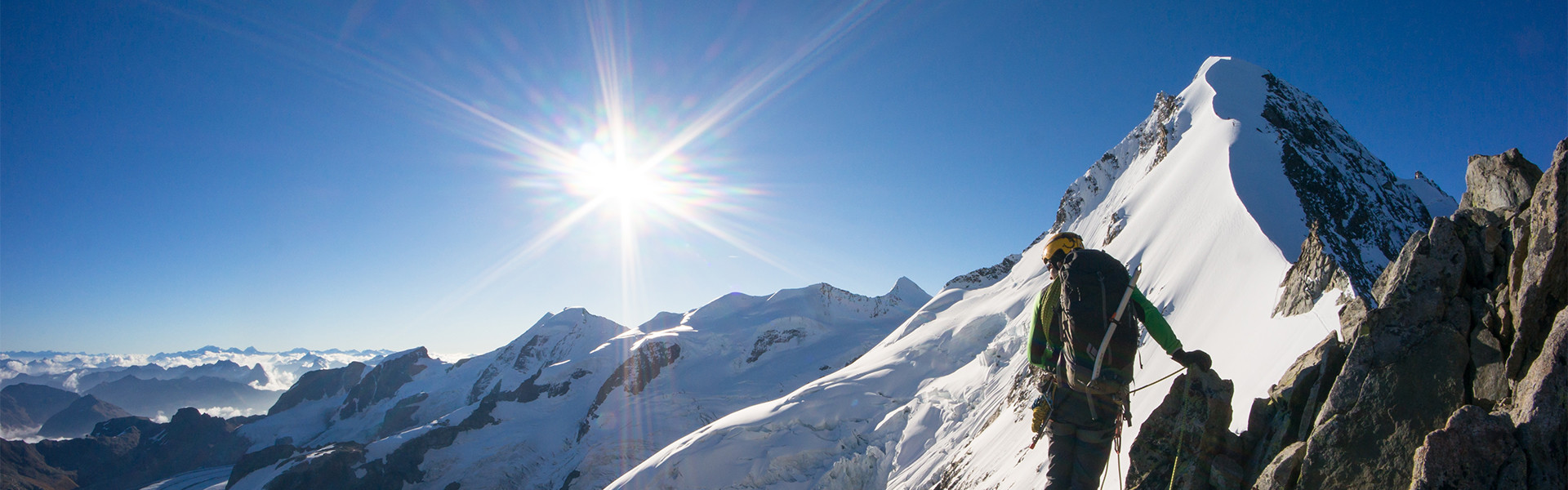 Bergsteiger bei Sonnenschein vor schneebedecktem Gipfel
