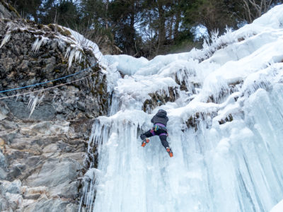 Eiskletterin in einem Eisvorhang und Felsbereich im Nachstieg.