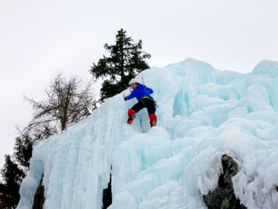 Eiskletterin an blumig blauem Eis.
