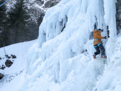Eiskletterin steigt an gefrorenem Wasser mit Eisgeräte empor.
