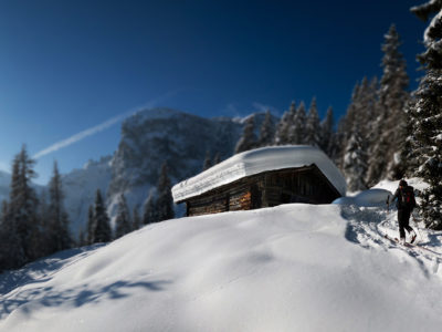 Zwei Skitourengeher in verschneiter Winterlandschaft vor Hütte