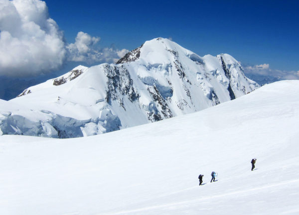 Drei Bergsteiger im Schnee auf dem Weg zum Gipfel