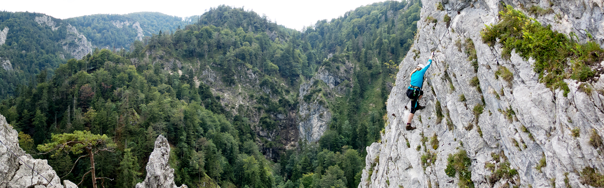 Klettersteiggeherin auf steiler Felswand